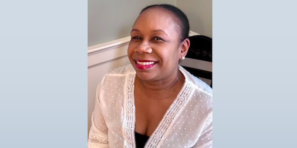 Smiling portrait of Nikki Mosgrove, Presiding Clerk of Philadelphia Yearly Meeting, wearing a white blouse with lace details. Nikki is known for her leadership among Quaker communities, dedication to inclusivity, and fostering young leadership within PYM.