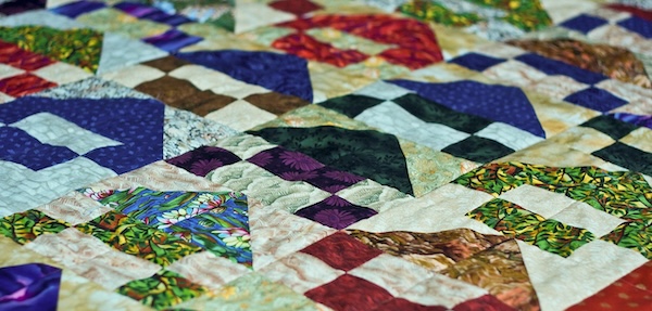 Close-up of a colorful handmade quilt with intricate stitching and vibrant patterns, symbolizing the interconnected gifts and diversity of the Quaker community.